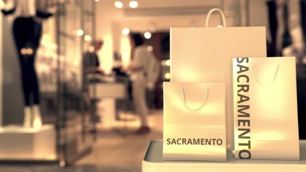 Torebki na zakupy z napisem Sacramento przed zamazanym wejściem do sklepu. Zakupy w Stanach Zjednoczonych związane z animacją 3D — Wideo stockowe
