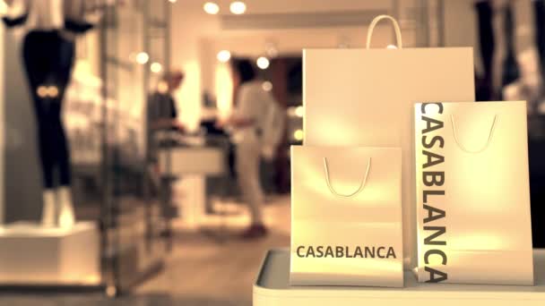 Torby na zakupy z napisem Casablanca przed zamazanym wejściem do sklepu. Zakupy w Maroko związane koncepcyjny animacja 3D — Wideo stockowe