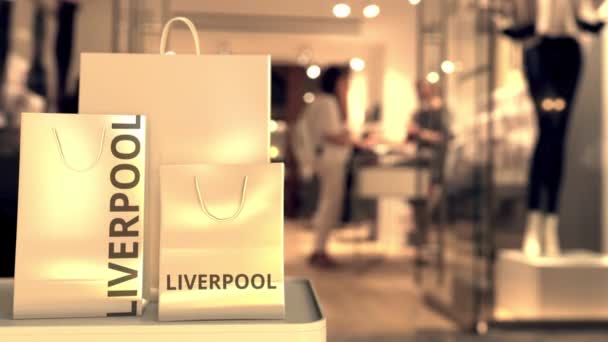 Papierowe torby na zakupy z napisem Liverpool przed niewyraźnym wejściem do sklepu. Detaliczna animacja koncepcyjna 3D w Zjednoczonym Królestwie — Wideo stockowe