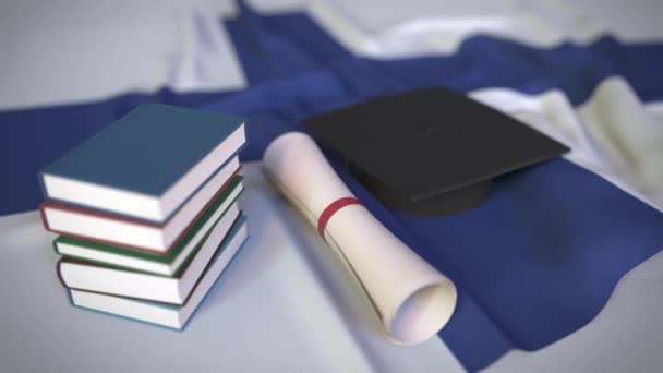 Boné de formatura, livros e diploma na bandeira finlandesa. Ensino superior na Finlândia relacionado animação 3D conceitual — Vídeo de Stock