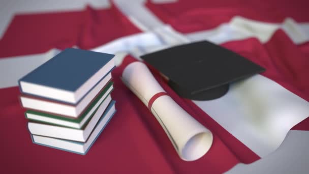 Выпускной колпак, книги и диплом на датском флаге. Концептуальная 3D анимация высшего образования в Дании — стоковое видео