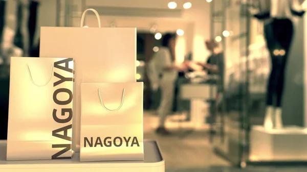 Sacos de compras de papel com legenda Nagoya contra a entrada da loja turva. Retalho no Japão renderização 3D relacionada — Fotografia de Stock