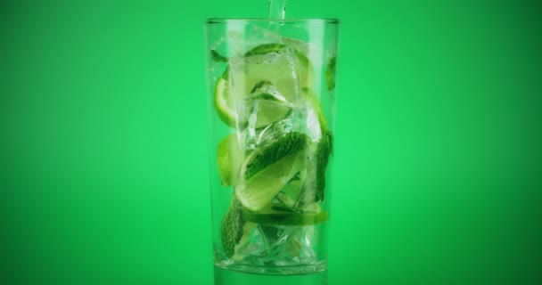 Herstellung von Mojito-Cocktail in einem Glas auf grünem Hintergrund, Nahaufnahme Zeitlupe auf Rot — Stockvideo