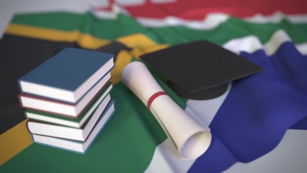 Mezuniyet şapkası, bayrağın üzerinde kitaplar ve diploma. Güney Afrika 'da yüksek öğrenim kavramsal 3d animasyonla ilgili — Stok video