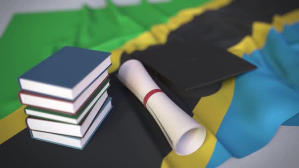 Tapa de graduación, libros y diploma en la bandera de Tanzania. La educación superior en Tanzania relacionados con la animación 3D conceptual — Vídeos de Stock