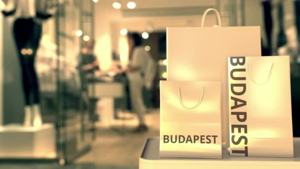 Bolsas de compras con leyenda de Budapest contra la entrada borrosa de la tienda. Compras en Hungría animación 3D relacionada — Vídeo de stock