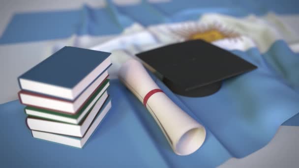 Tapa de graduación, libros y diploma en la bandera argentina. Educación superior en Argentina relacionada con la animación conceptual 3D — Vídeos de Stock