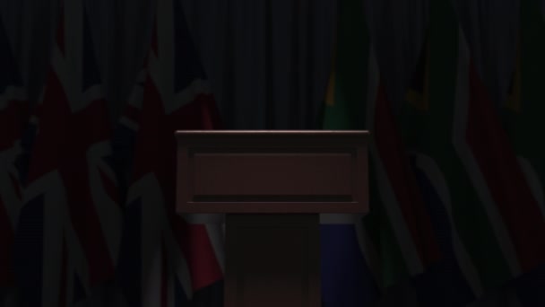Row of flags of South Africa and the United Kingdom and and speaker tribune, conceptual 3D animation — Stock Video
