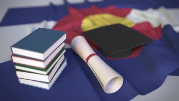Végzős sapka, könyvek és oklevelek Colorado zászlóján. Felsőoktatás az Egyesült Államokkal kapcsolatos koncepció 3D animáció — Stock videók