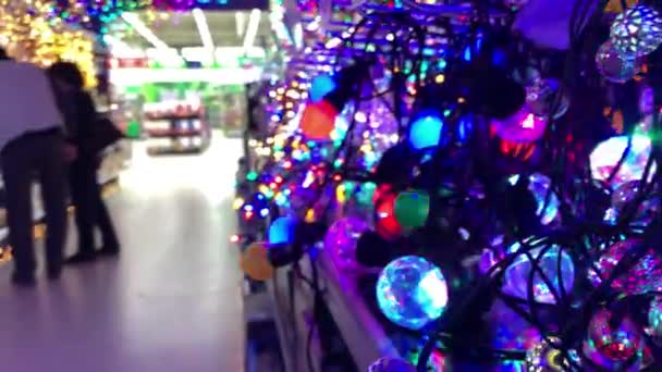 Unknowns customers choose LED Christmas tree lights in a big store — Stock Video