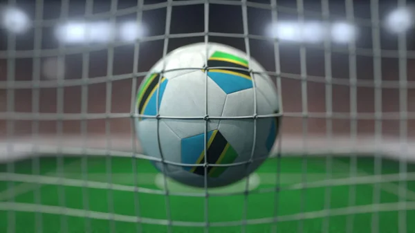 El fútbol con banderas de Tanzania golpea la red de goles. Renderizado 3D — Foto de Stock