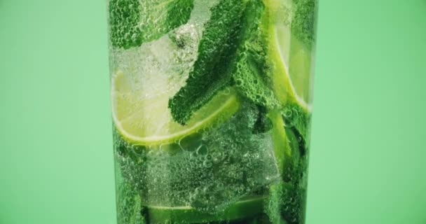 Makroaufnahme eines Mojito-Cocktails im Glas vor grünem Hintergrund — Stockvideo