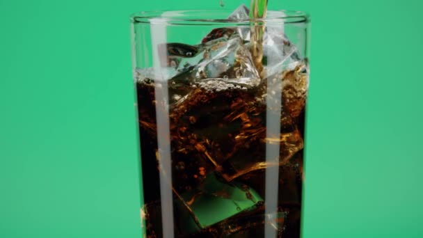 将可乐软饮料倒入装有绿色背景冰块的杯子中，特写慢镜头射向红色 — 图库视频影像