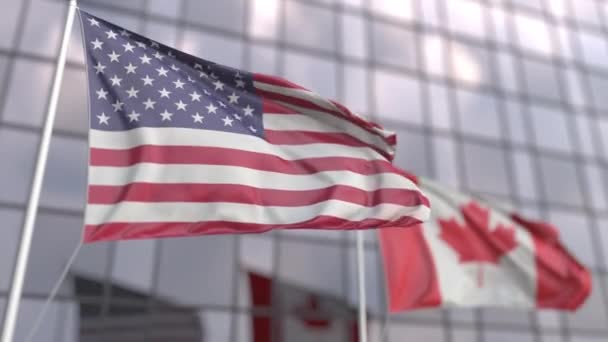 Ondeando banderas de los Estados Unidos y Canadá frente a una moderna fachada de rascacielos — Vídeos de Stock