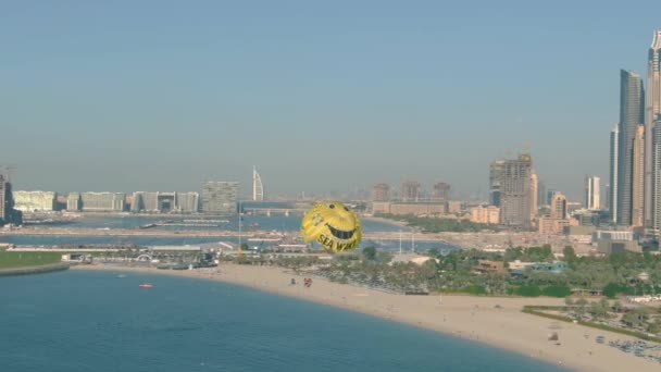 Dubai, Verenigde Arabische Emiraten - 26 december 2019. Luchtfoto van Seawake parasailing tegen wolkenkrabbers en strand aan het water — Stockvideo