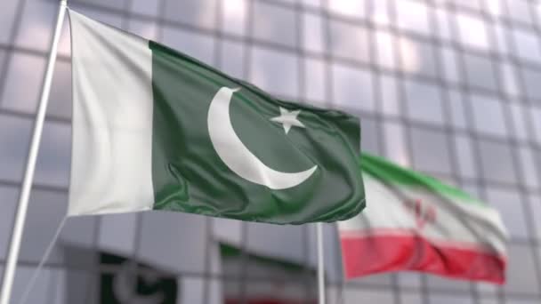 Zwaaiende vlaggen van Pakistan en Iran voor een moderne wolkenkrabbergevel — Stockvideo