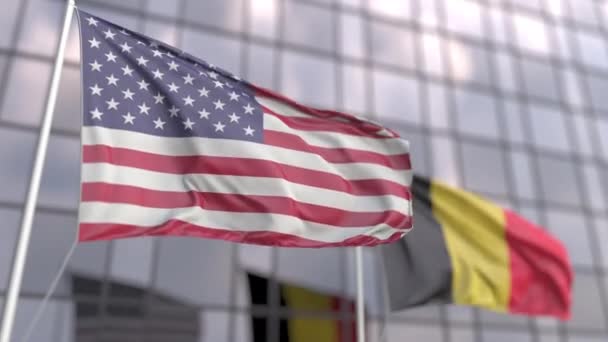 Flaggen der USA und Belgiens vor einer modernen Hochhausfassade schwenken — Stockvideo