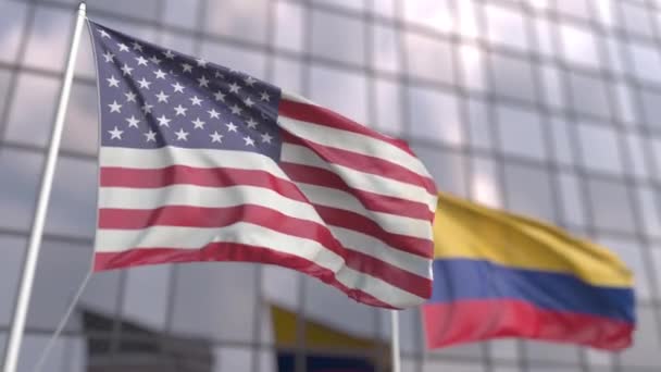 Ondeando banderas de Estados Unidos y Colombia frente a una moderna fachada de rascacielos — Vídeo de stock