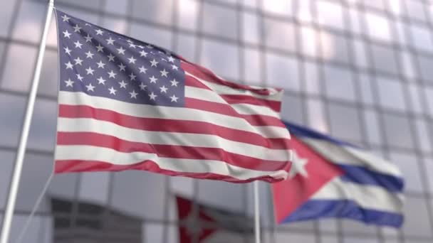 Vlnící se vlajky USA a Kuby před moderní fasádou mrakodrapu — Stock video