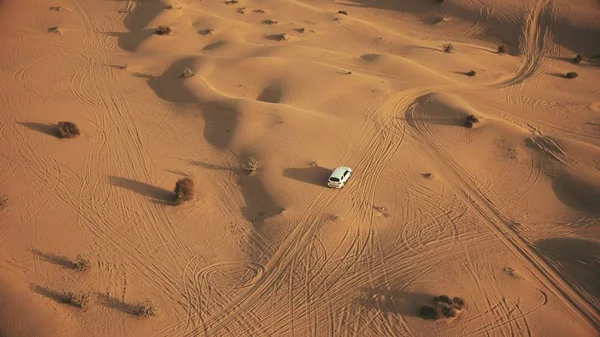 Снимок большой белой машины, движущейся по песчаным дюнам пустыни — стоковое фото