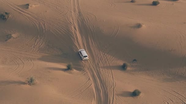 Luftaufnahme eines unbekannten weißen Geländewagens, der schnell über Sanddünen in der Wüste fährt, uae — Stockvideo