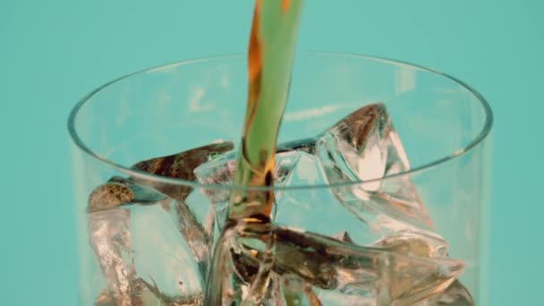 Налить коричневый безалкогольный напиток в стакан, полный кубиков льда, на голубом фоне, замедленная съемка на Красном — стоковое видео