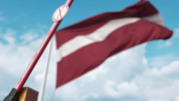 Puerta de la barrera sin señal de inmigración que se cierra con la bandera de Letonia como fondo. Cruce fronterizo restringido de Letonia o prohibición de inmigración — Vídeo de stock