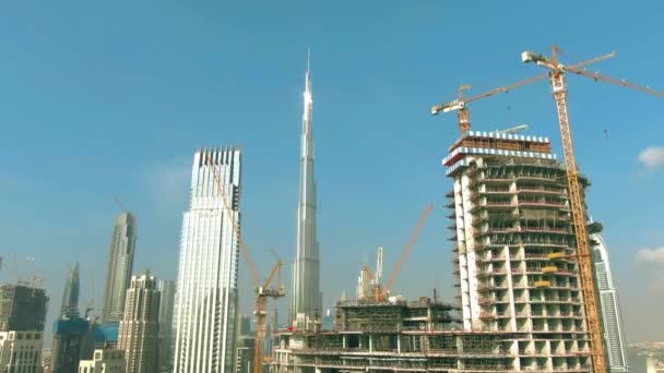 ドバイ、アラブ首長国連邦- 2019年12月30日。高層ビル建設現場の背後にあるブルジュ・ハリファ塔の空中撮影 — ストック動画