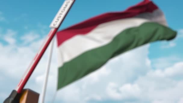 Zamknięta brama boom z oznaczeniem celnym na tle węgierskiej flagi. Zamknięcie granic lub taryfy ochronne na Węgrzech — Wideo stockowe