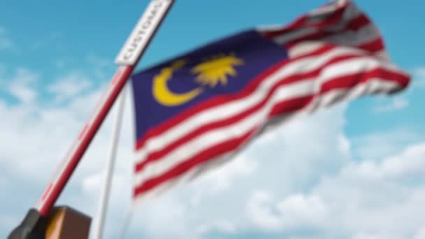 Барьерные ворота с табличкой CUSTOMS закрываются на фоне флага Малайзии. Ограниченные границы Малайзии или защитные тарифы — стоковое видео