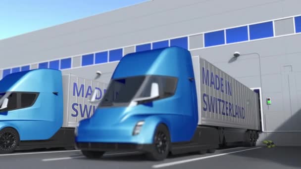 Camions semi-remorques modernes avec texte MADE IN SWITZERLAND chargé ou déchargé en entrepôt. Animation 3D bouclable liée à l'entreprise suisse — Video