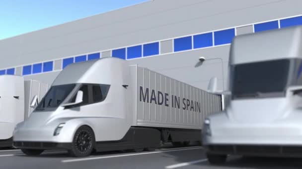 Modernos camiones semirremolques con texto MADE IN SPAIN cargado o descargado en almacén. Animación 3D loopable relacionada con el negocio español — Vídeo de stock