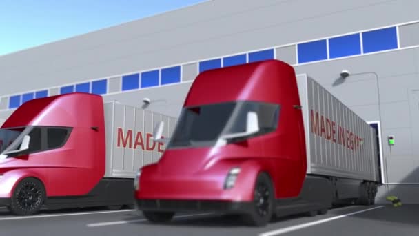 Caminhões semi-reboque modernos com texto MADE IN EGYPT sendo carregado ou descarregado no armazém. egípcio negócios relacionados loopable animação 3D — Vídeo de Stock