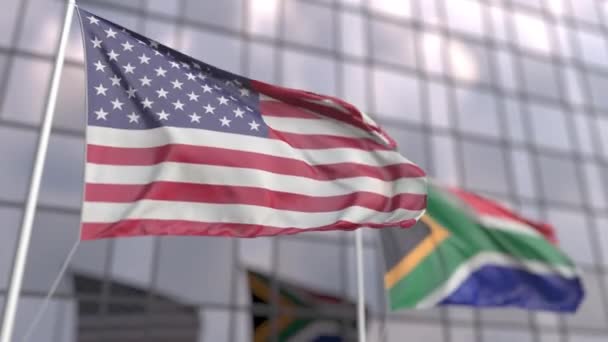 Flying flags of the United States and South Africa in front of a modern skyscraper — Stock Video