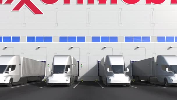 Elektromos félpótkocsik rakodótérben Exxon Mobil Corporation logóval a falon. Szerkesztőségi 3D animáció — Stock videók