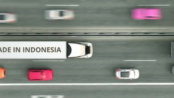 Bovenaanzicht vanuit de lucht van opleggertrucks met Made In Indonesia tekst die langs de weg rijdt. Indonesische business gerelateerde loopable 3d animatie — Stockvideo