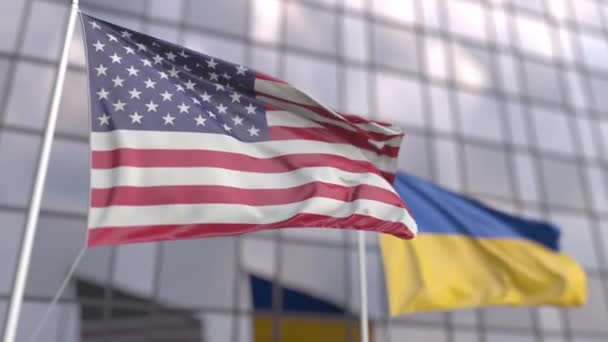 Flaggen der Vereinigten Staaten und der Ukraine vor einer Fassade eines modernen Gebäudes schwenken — Stockvideo