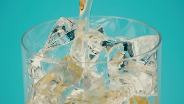 Verser de la limonade dans un verre avec des glaçons sur fond cyan, gros plan sur Rouge — Video