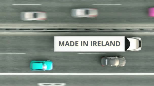 Vista aérea de arriba hacia abajo de camiones semirremolque con texto MADE IN IRELAND conduciendo a lo largo de la carretera. Turco negocio relacionado loopable animación 3D — Vídeo de stock