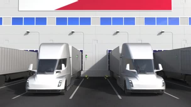 Electric semi-trailer trucks at warehouse loading bay with flag of BAHRAIN. Bahraini logistics related conceptual 3D animation — Stock Video