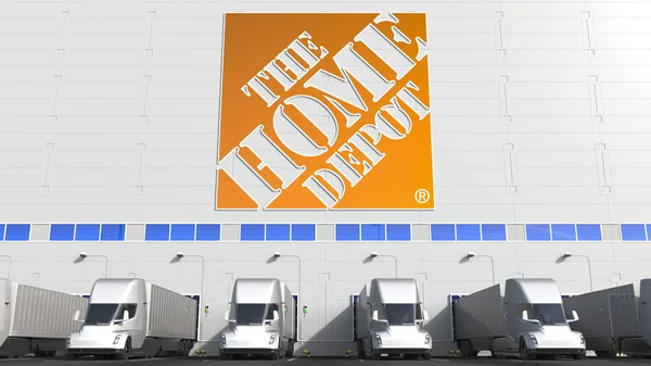 Elektromos félpótkocsik a raktár rakodóterében, a Home Depot logóval a falon. Szerkesztőségi 3D-s renderelés — Stock Fotó