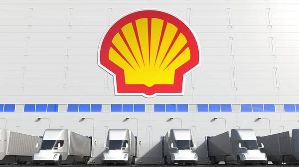 Elektryczne przyczepy w magazynie ładowni z logo Royal Dutch Shell na ścianie. Redakcja 3d renderowania — Zdjęcie stockowe