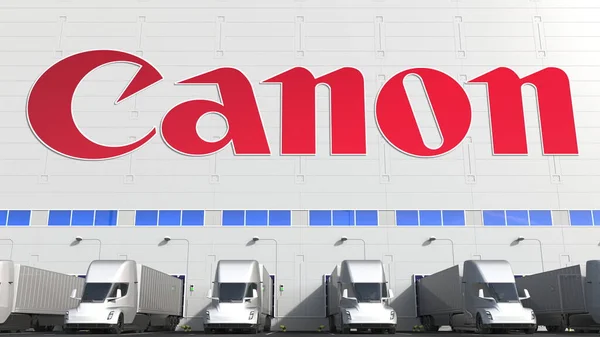 Електричні напівпричепні вантажівки на складі вантажного відсіку з логотипом CANON на стіні. Редакція 3D рендеринга — стокове фото