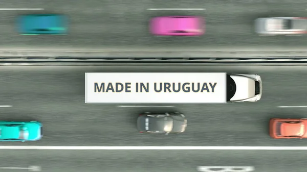 半挂车空中俯瞰图，带有MADE IN URUGUAY文字，沿着公路行驶。乌拉圭业务相关3D渲染 — 图库照片