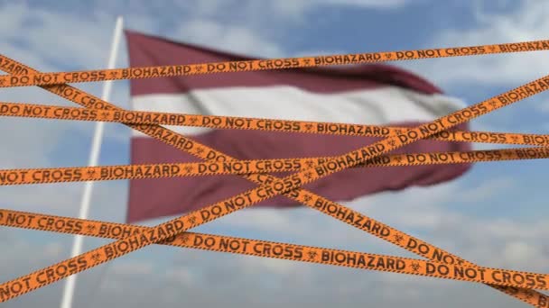 Precaución cinta de riesgo biológico con la bandera de Letonia como fondo. Cruce fronterizo restringido letón o cuarentena. Animación en 3D de bucle conceptual — Vídeo de stock