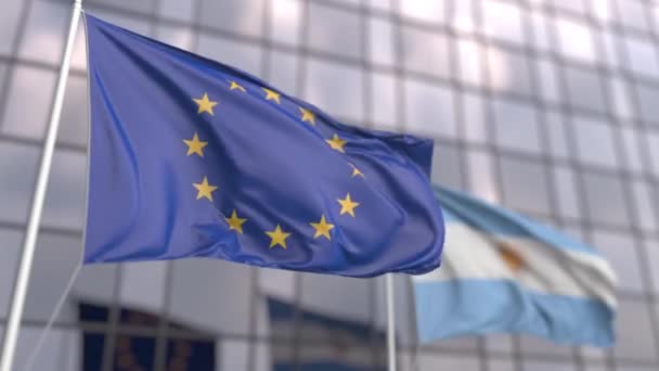 Ondeando banderas de la UE y Argentina frente a una moderna fachada de rascacielos — Vídeo de stock