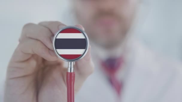 Doctor holds stethoscope bell with the Thai flag. Healthcare in Thailand — Stock Video