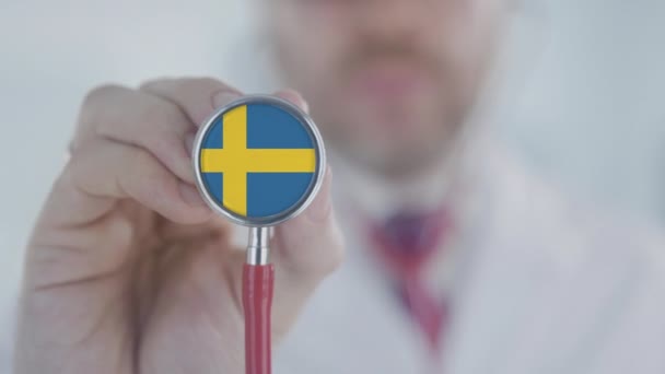 Medical doctor holds stethoscope bell with the Swedish flag. Healthcare in Sweden — Stock Video