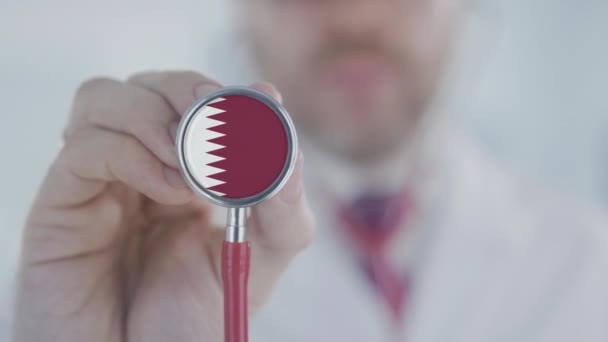 Doktor, Katar bayrağıyla steteskopla dinliyor. Katarlı sağlık hizmetleri — Stok video