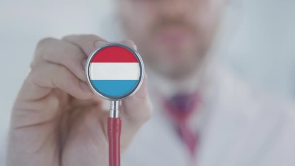 Dokter die luistert met de stethoscoop met de vlag van Luxemburg. Luxemburgse gezondheidszorg — Stockvideo